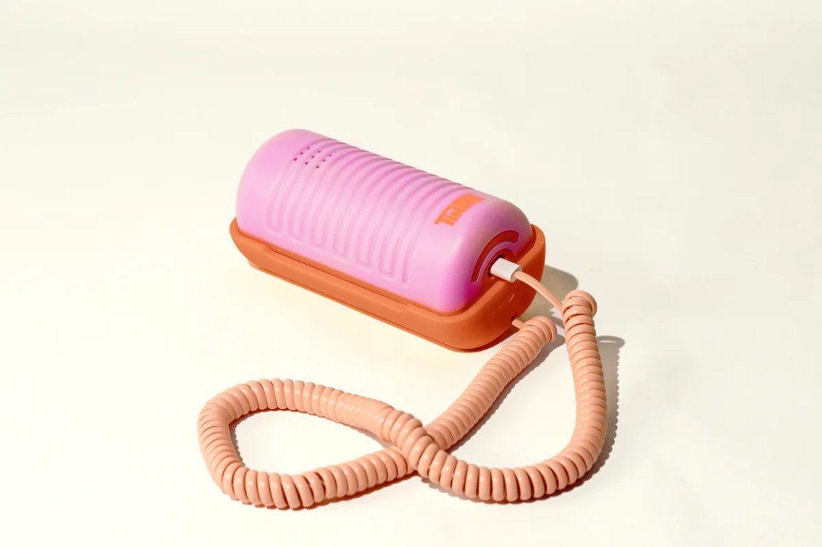 A retro-inspired corded phone design in pink and orange, featuring a coiled cord and minimalist style.