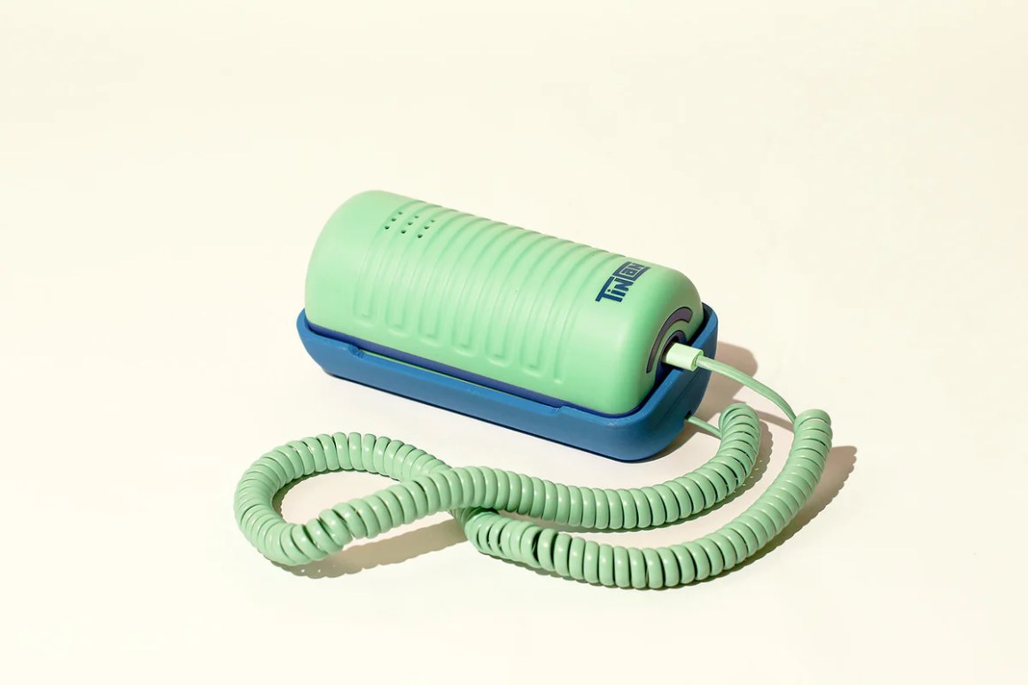 A green and blue corded landline phone named 'Tin Can' sits on a plain background, showcasing its retro design with a modern twist.
