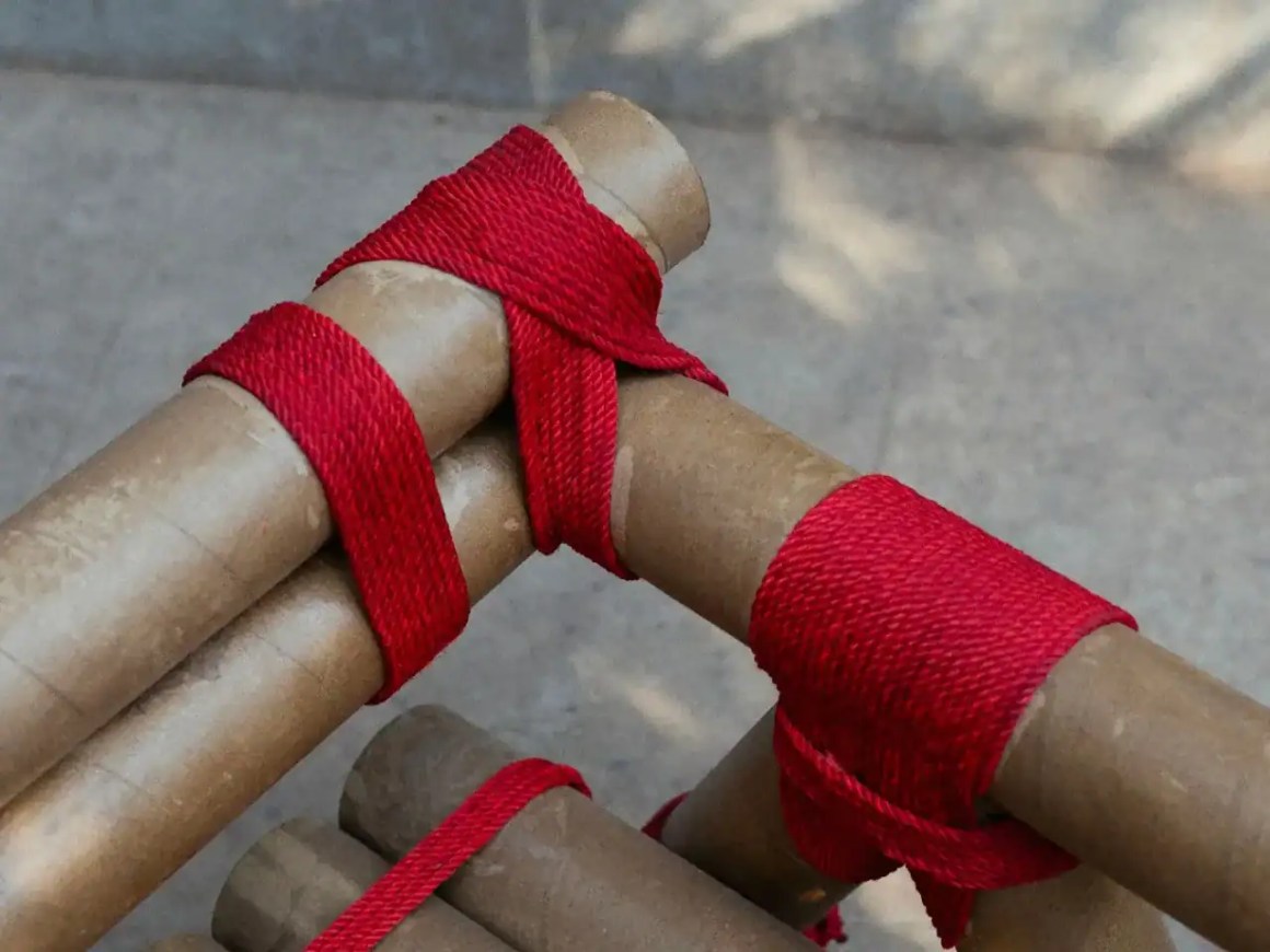 Close-up of bamboo sticks wrapped with bright red fabric, showcasing intricate bindings.