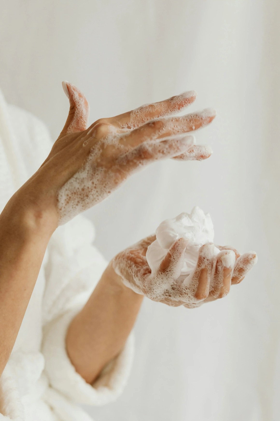 Close-up of a person's hands covered in foam, one hand holding a soapy lather while the other is gesturing.